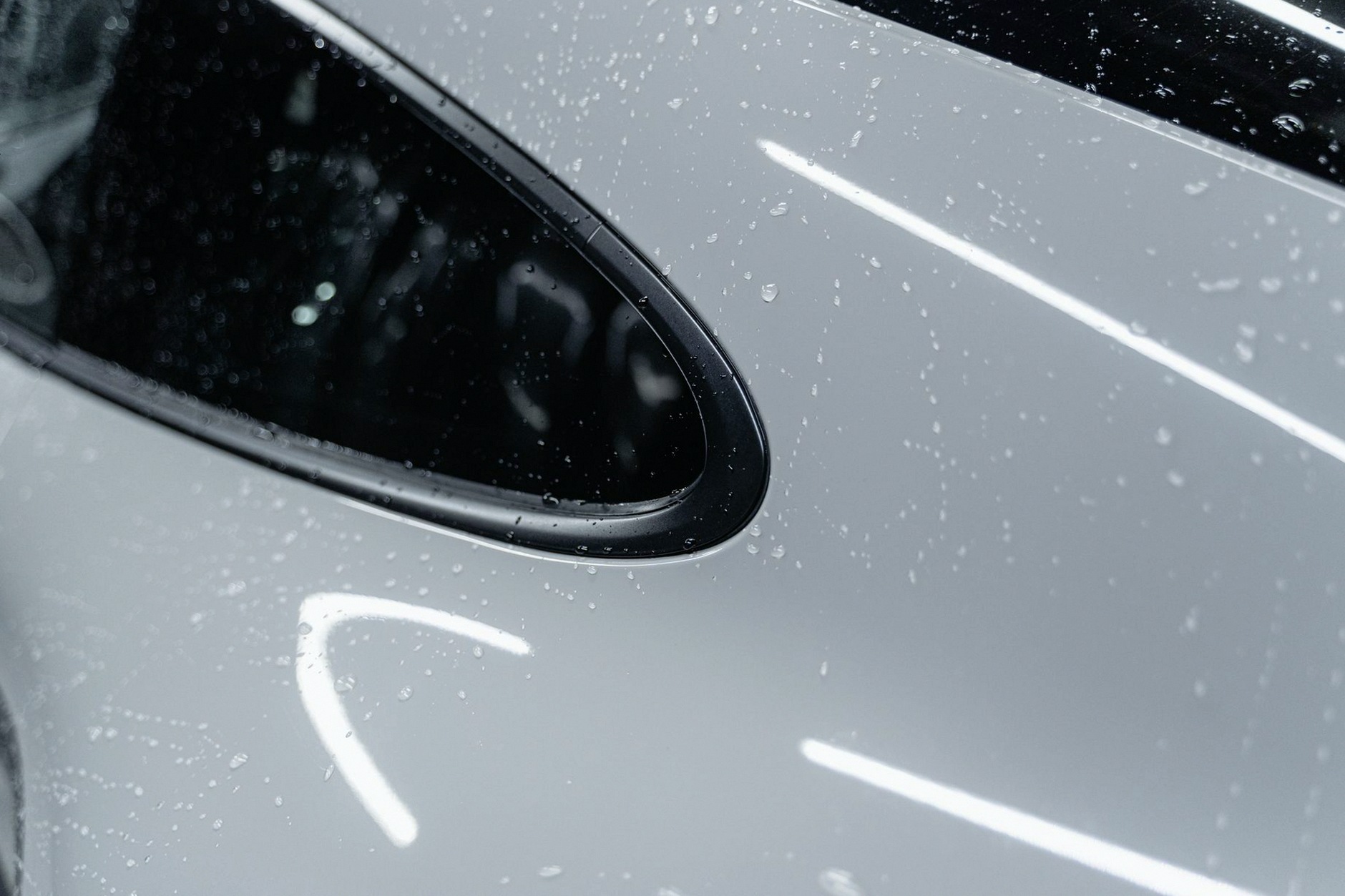 A detailed view of a white car with water droplets after a wash, showcasing its shine.