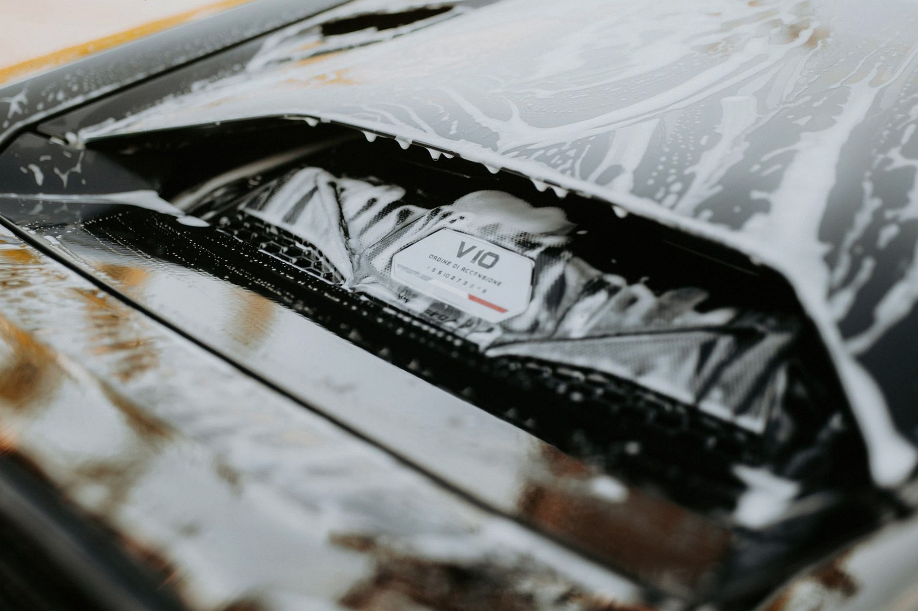 Detailed image of a sleek car being washed with foam, showcasing the car's design and cleanliness.